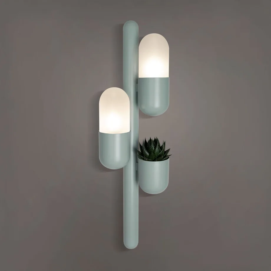 Cactus wall lamp lacquered in cement gray, featuring opal glass and a succulent plant, with the lights turned on.