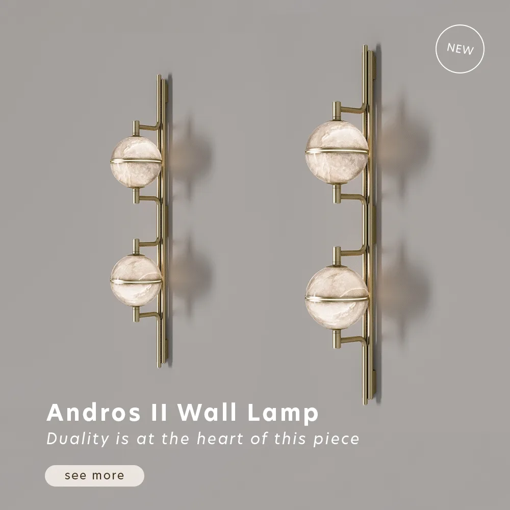 Animated image showcasing two Andros II Wall Lamps by Creativemary, turning lights on and off, mounted side-by-side on a muted gray wall. Each lamp features a sleek, vertical brushed-brass spine that serves as a minimalist anchor. Attached to the spine are two glowing, spherical alabaster lampshades that emit a warm, translucent light, highlighting the natural stone’s unique veining. The lamps appear to subtly shift angles, showcasing their sculptural silhouette, cast shadows, and modern "wall jewelry" design.